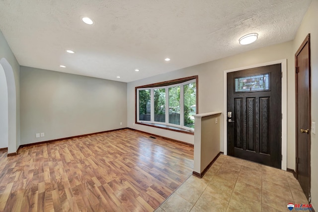 entrance foyer with baseboards, light wood-style flooring, recessed lighting, and a textured ceiling