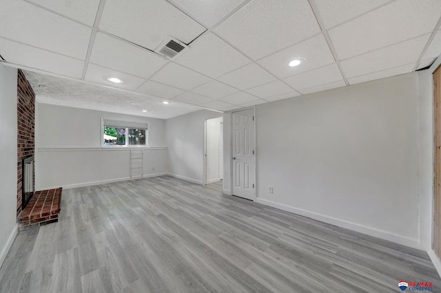 below grade area with wood finished floors, baseboards, recessed lighting, a fireplace, and a paneled ceiling