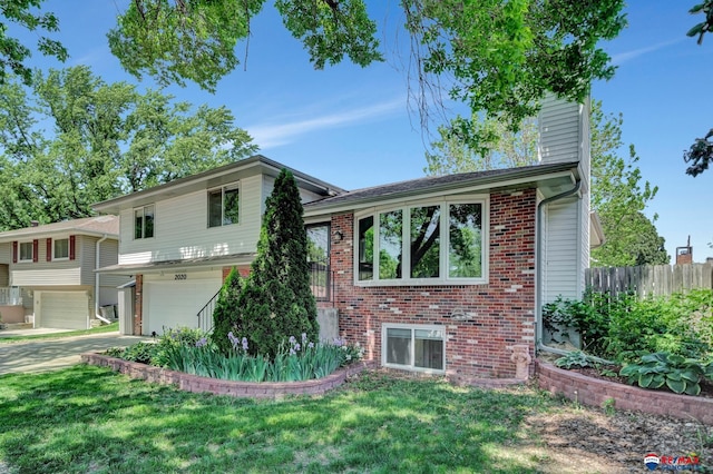 split level home featuring a garage, brick siding, and driveway
