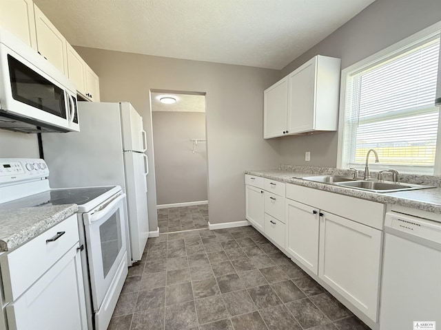 4227 N 57th St, Lincoln, NE 68507 - kitchen featuring white appliances, a sink, baseboards, white cabinetry, and light countertops