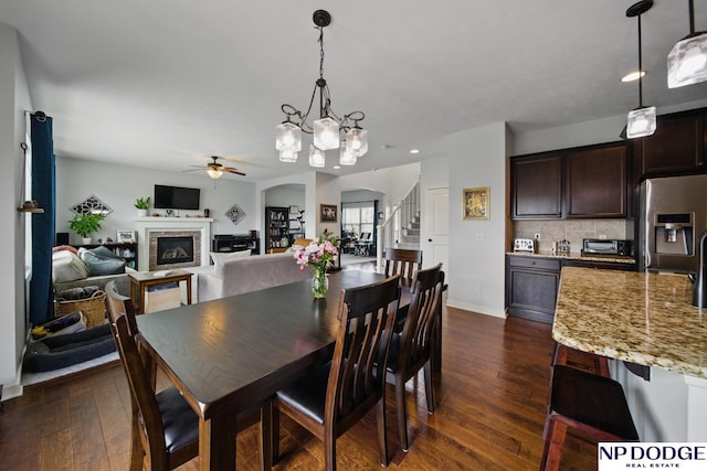 dining room featuring a ceiling fan, dark wood-type flooring, arched walkways, stairway, and recessed lighting