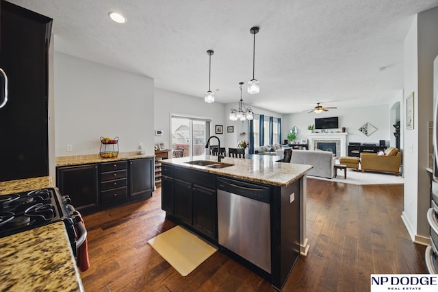 kitchen featuring stainless steel dishwasher, a sink, dark wood-style floors, a fireplace, and ceiling fan