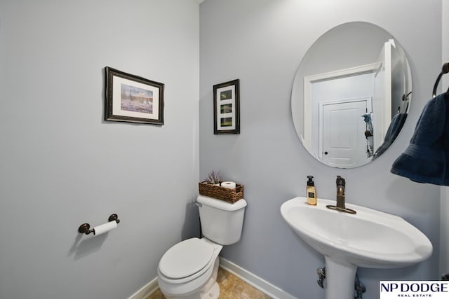 bathroom featuring toilet, baseboards, and a sink