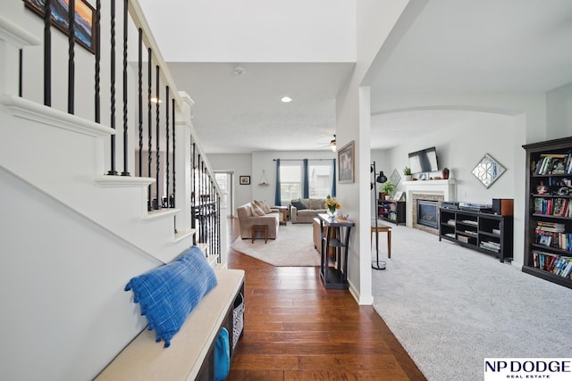 foyer featuring a glass covered fireplace, dark wood-type flooring, stairs, recessed lighting, and a ceiling fan