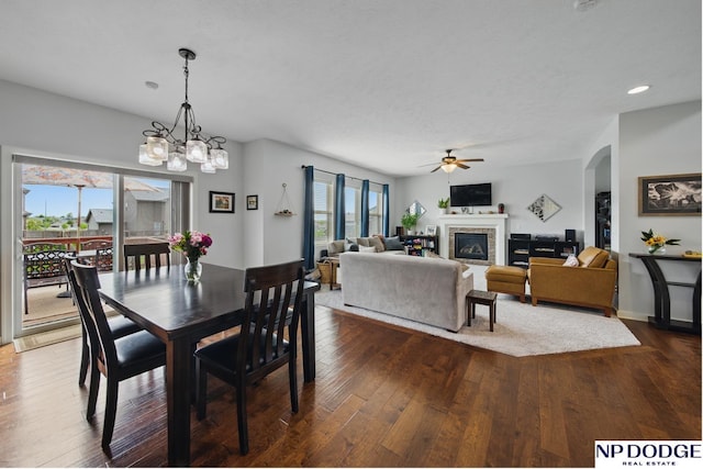 dining area with dark wood-type flooring, a glass covered fireplace, arched walkways, a ceiling fan, and recessed lighting