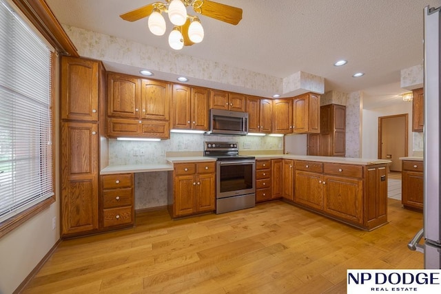 6630 Flint Ridge Rd, Lincoln, NE 68506 - kitchen with appliances with stainless steel finishes, brown cabinetry, light wood-style floors, light countertops, and recessed lighting