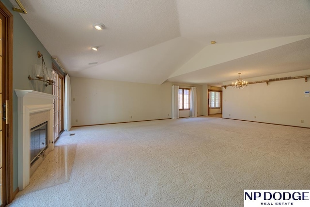 6630 Flint Ridge Rd, Lincoln, NE 68506 - unfurnished living room with a chandelier, vaulted ceiling, light colored carpet, a glass covered fireplace, and baseboards