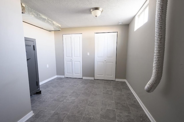 56420 708th Rd, Fairbury, NE 68352 - unfurnished bedroom featuring multiple closets, a textured ceiling, and baseboards