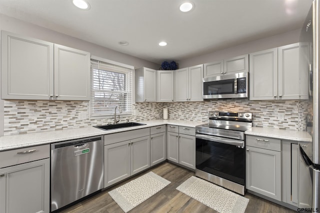kitchen featuring appliances with stainless steel finishes, a sink, light countertops, recessed lighting, and dark wood-style floors