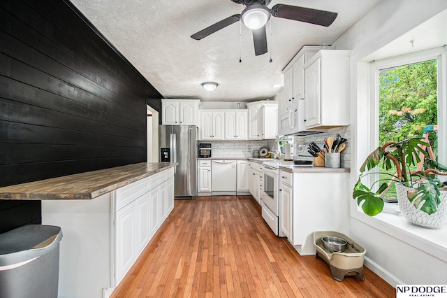kitchen with white appliances, ceiling fan, white cabinetry, backsplash, and light wood-style floors