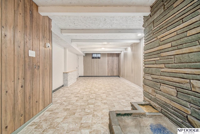 corridor with wood walls, beamed ceiling, baseboards, and stone finish flooring