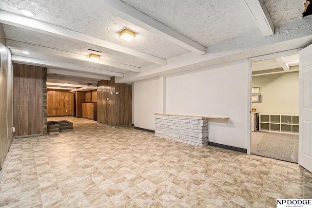 finished below grade area featuring wood walls, baseboards, and tile patterned floors