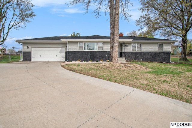 ranch-style home with driveway, brick siding, an attached garage, and a chimney