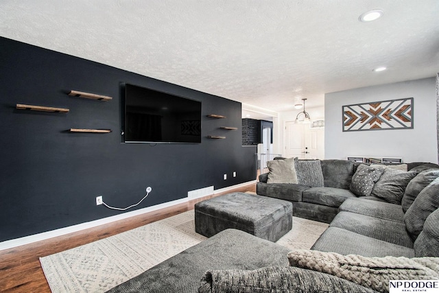 living room featuring baseboards, wood finished floors, recessed lighting, and a textured ceiling