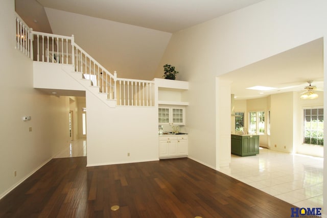 6427 Lone Tree Dr, Lincoln, NE 68512 - unfurnished living room featuring a ceiling fan, a towering ceiling, wood finished floors, stairs, and baseboards