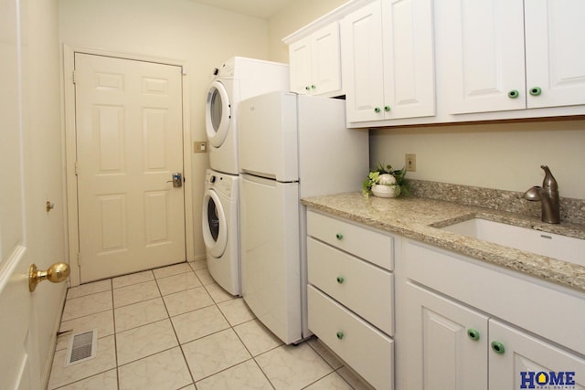 6427 Lone Tree Dr, Lincoln, NE 68512 - laundry room with stacked washer and clothes dryer, cabinet space, and light tile patterned floors