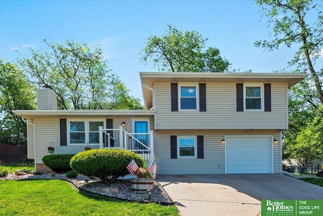 tri-level home with concrete driveway, fence, an attached garage, and a chimney