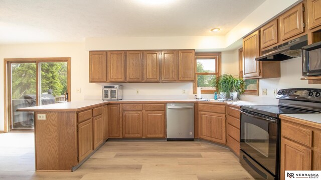 719 Cory Dr, Seward, NE 68434 - kitchen with stainless steel dishwasher, electric range, a peninsula, under cabinet range hood, and light countertops