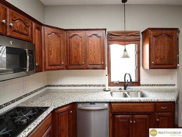 kitchen with stainless steel appliances, a sink, decorative backsplash, and light stone countertops