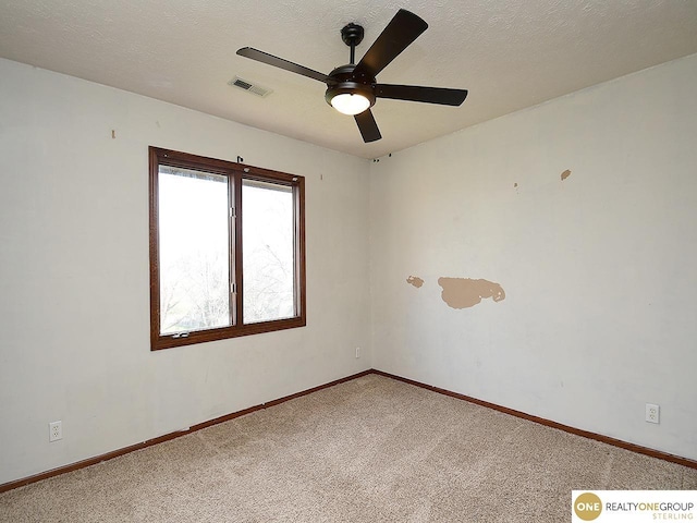 unfurnished room featuring ceiling fan, light colored carpet, baseboards, and a textured ceiling