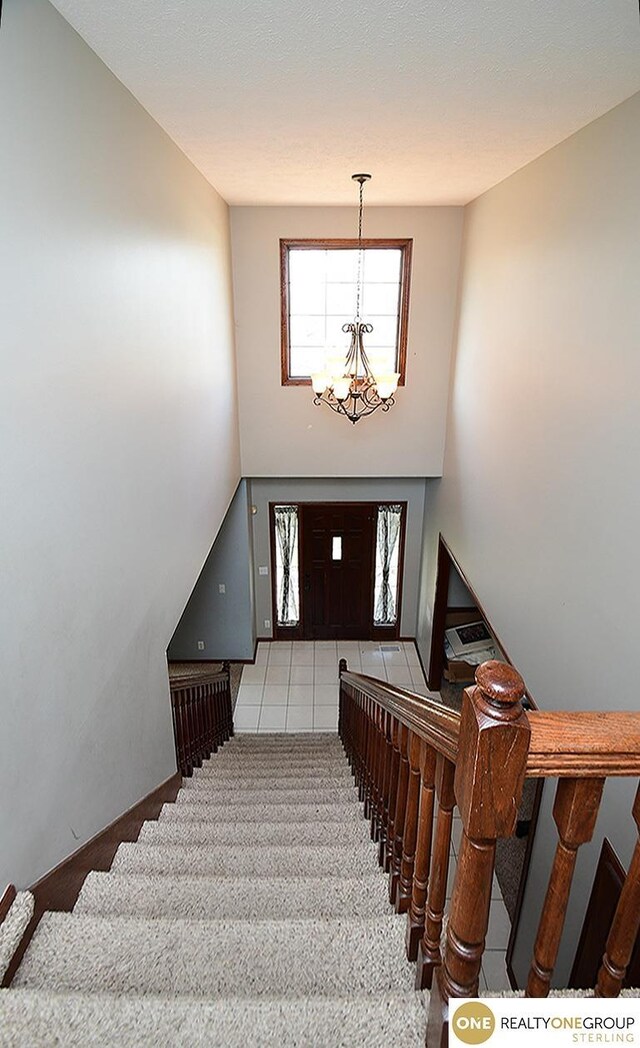 stairs featuring a chandelier and carpet