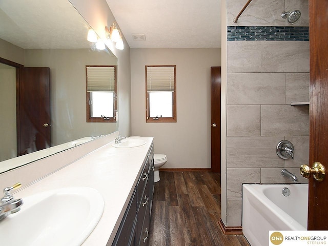 bathroom featuring wood finished floors, double vanity, baseboards, and toilet