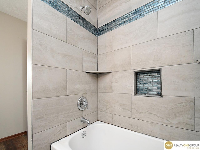 bathroom featuring wood finished floors, shower / bath combination, and baseboards