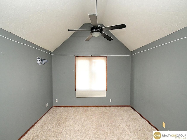 unfurnished room with a ceiling fan, vaulted ceiling, carpet floors, and baseboards