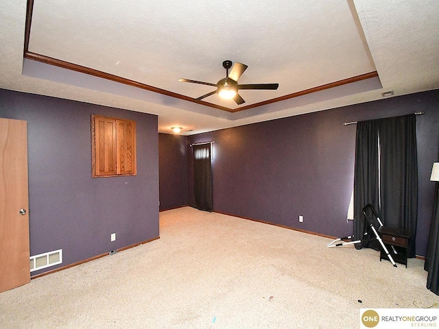 spare room featuring a raised ceiling, a ceiling fan, baseboards, carpet flooring, and ornamental molding