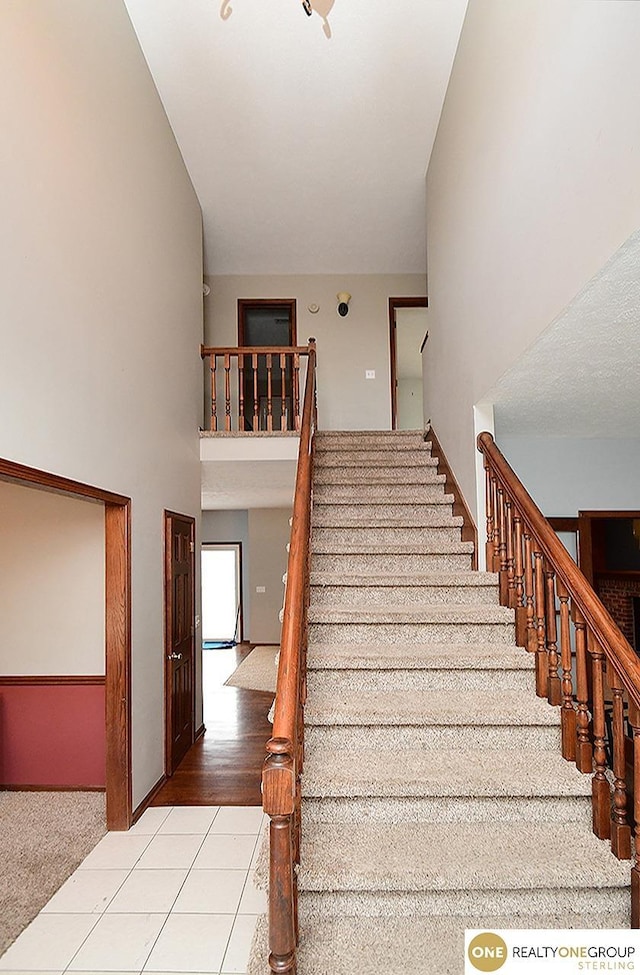 stairway featuring a high ceiling and tile patterned floors