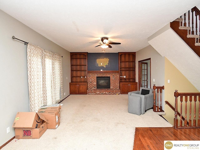 unfurnished living room with a ceiling fan, built in features, carpet, a brick fireplace, and baseboards