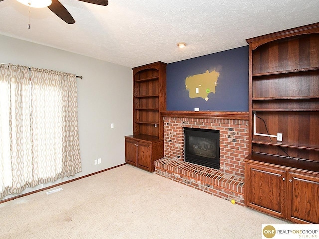 unfurnished living room featuring ceiling fan, a brick fireplace, carpet floors, baseboards, and a textured ceiling