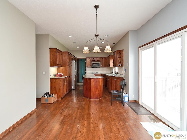 kitchen featuring appliances with stainless steel finishes, a kitchen island, healthy amount of natural light, dark wood finished floors, and recessed lighting