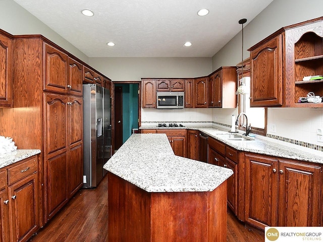 kitchen with appliances with stainless steel finishes, dark wood finished floors, a kitchen island, backsplash, and a sink