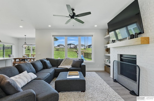 living room with wood finished floors, recessed lighting, ceiling fan, baseboards, and a fireplace