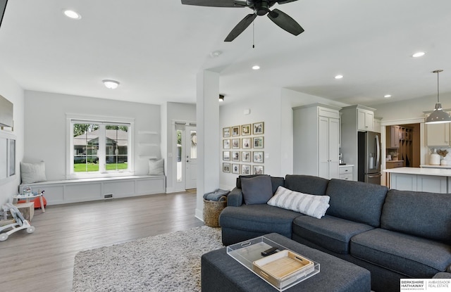 living room featuring light wood-style flooring, a ceiling fan, and recessed lighting
