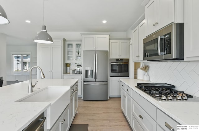 kitchen featuring stainless steel appliances, a sink, white cabinets, backsplash, and recessed lighting