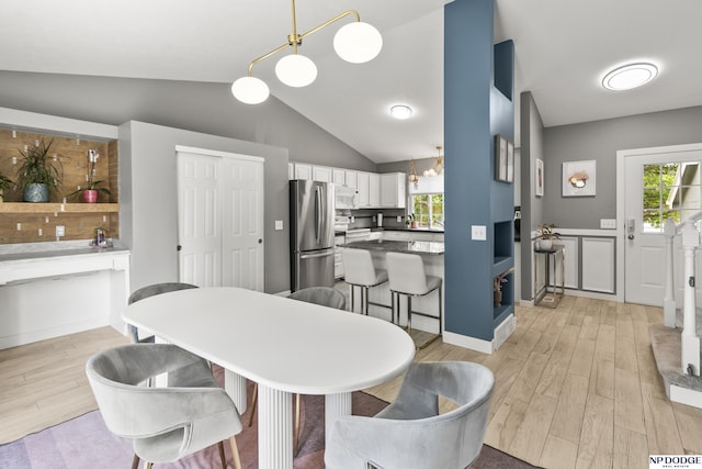 18667 R St, Omaha, NE 68135 - kitchen featuring freestanding refrigerator, light wood-style flooring, white cabinets, vaulted ceiling, and a breakfast bar area