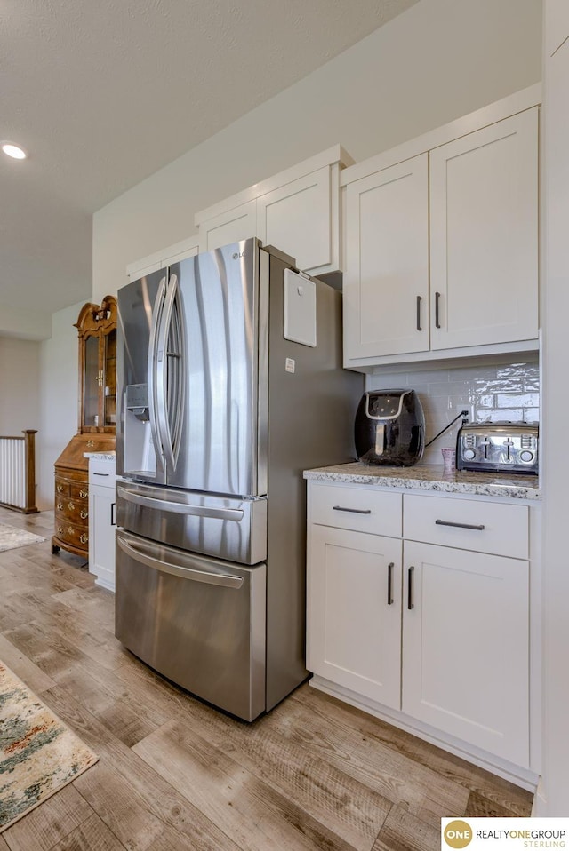 12618 Glenn St, Omaha, NE 68138 - kitchen with stainless steel fridge with ice dispenser, white cabinetry, light wood-type flooring, decorative backsplash, and light stone countertops