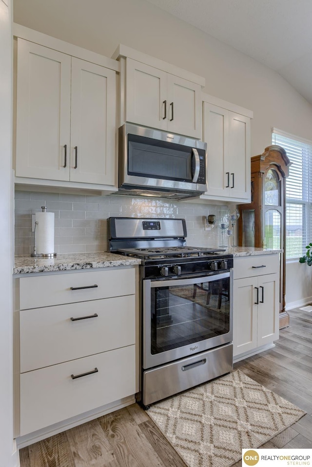 12618 Glenn St, Omaha, NE 68138 - kitchen featuring appliances with stainless steel finishes, light wood-style floors, white cabinetry, tasteful backsplash, and vaulted ceiling