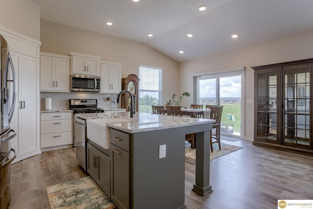 12618 Glenn St, Omaha, NE 68138 - kitchen featuring appliances with stainless steel finishes, lofted ceiling, a breakfast bar area, wood finished floors, and an island with sink
