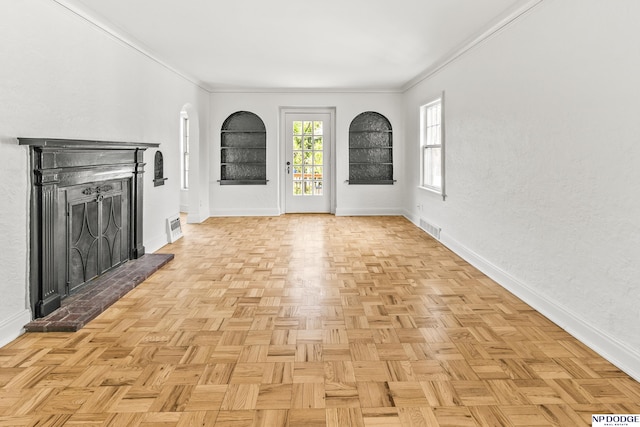 unfurnished living room featuring baseboards, ornamental molding, and arched walkways