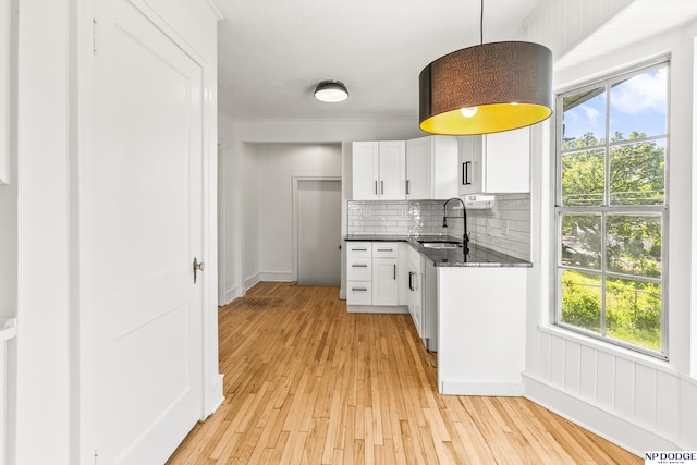 kitchen featuring a sink, light wood-type flooring, healthy amount of natural light, and white cabinets