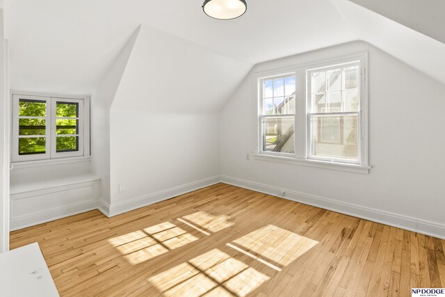 additional living space featuring lofted ceiling, healthy amount of natural light, hardwood / wood-style floors, and baseboards