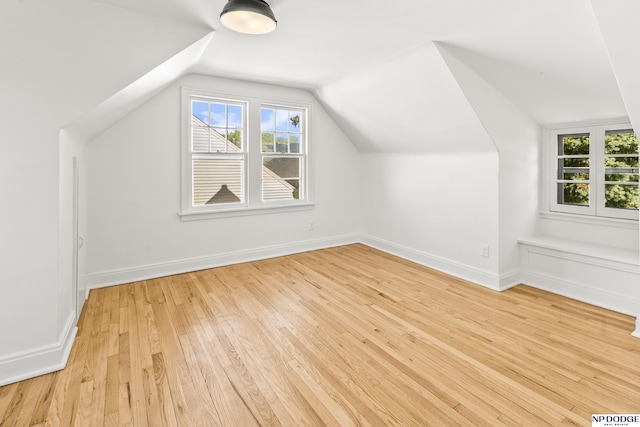 bonus room featuring lofted ceiling, light wood finished floors, and baseboards