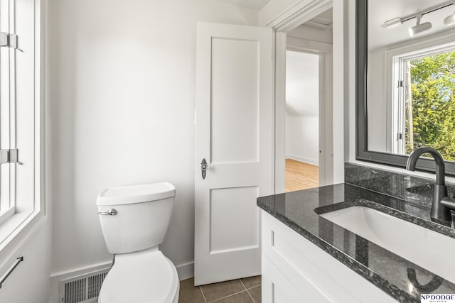 half bath with vanity, toilet, tile patterned flooring, and baseboards