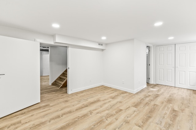 finished below grade area with light wood-style floors, stairway, recessed lighting, and baseboards