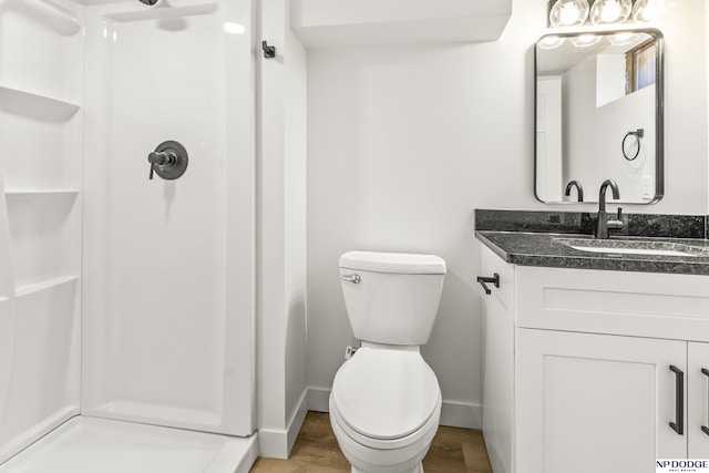 full bathroom with toilet, a stall shower, wood finished floors, vanity, and baseboards