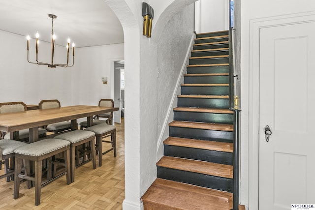 stairs featuring a chandelier and arched walkways