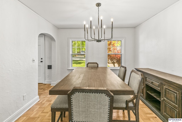 dining room featuring baseboards, arched walkways, a chandelier, ornamental molding, and a textured wall